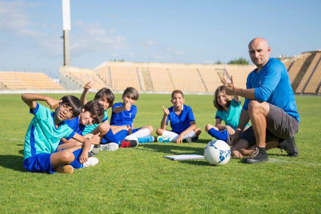 Coach reviewing video with players on the pitch